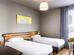 a hotel room with two beds and a table at Aparthotel Adagio Access Paris Vanves - Porte de Châtillon in Vanves