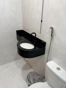 a bathroom with a toilet with a black shelf above it at Residencial Ebenezer conforto perto da ufac in Rio Branco