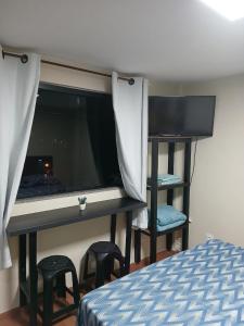 a bedroom with a desk and stools next to a bed at Loft Meu Aconchego in Nova Friburgo