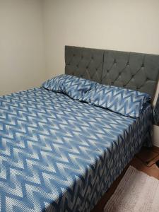 a bed with a blue and white comforter on it at Loft Meu Aconchego in Nova Friburgo