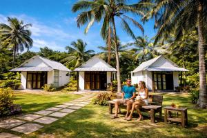 a family sitting on a bench in front of a resort at Velora Resort in Udawalawe