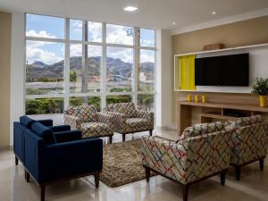 a living room with couches and a tv and large windows at Granterrara Hotel in Jequié