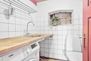 a white tiled kitchen with a sink and a washing machine at 20611-Samso-Brundby-Hovedgade-66 in Brundby +24 photos