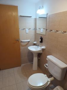 a bathroom with a white toilet and a sink at Complejo Los Arrayanes - Plottier in Plottier +4 photos