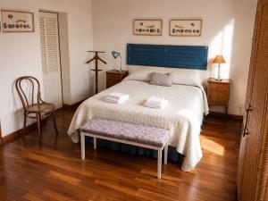 a bedroom with a bed with a blue headboard and a chair at Casa Verde in La Cumbre
