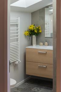baño con lavabo y jarrón de flores amarillas en Appartement 9 Place d'Alliance en Nancy