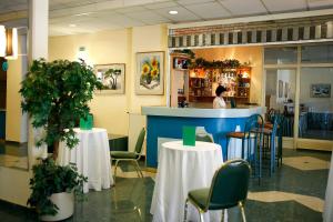 a restaurant with tables and chairs and a woman behind a counter at Hotel Bara Budapest in Budapest