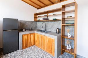 a kitchen with a black refrigerator and wooden cabinets at Arc Villas Bali in Ketewel
