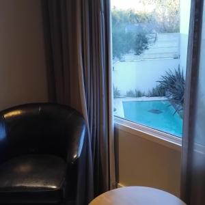 a chair in front of a window with a swimming pool at VICTORIA BED and BREAKFAST 1 A 3KM AEROPUERTO EZEIZA in Ezeiza