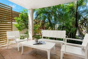 two white chairs and a table on a patio at Wallaby Beach House - Resort-style Comforts in Trinity Beach