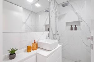 a white bathroom with a sink and a shower at Sunlit Apartment with Balcony & Atlantic Views in Ponta do Sol +21 photos