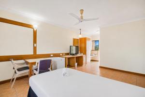 a room with a bed and a desk and a tv at The Reef Motel in Cairns