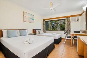 a bedroom with a large bed and a kitchen at The Reef Motel in Cairns