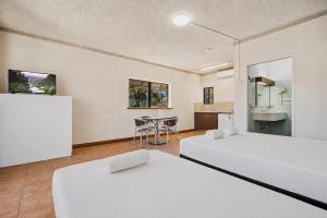 two beds in a room with a kitchen and a table at The Reef Motel in Cairns +4 photos