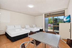 a room with a bed and a table and chairs at The Reef Motel in Cairns