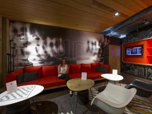 a woman sitting on a red couch in a room at Ibis Vienna Airport in Schwechat