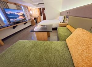 a hotel room with a bed and a couch and a tv at Fosen Hotel in Taichung