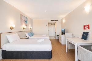 ein Hotelzimmer mit zwei Betten und einem Schreibtisch in der Unterkunft The Oceanfront in Cairns