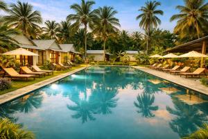 a pool at a resort with chairs and palm trees at Velora Resort in Udawalawe