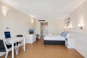 ein weißes Zimmer mit einem Bett, einem Schreibtisch und einem Tisch in der Unterkunft The Oceanfront in Cairns
