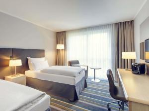 a hotel room with two beds and a desk at Mercure Düsseldorf Kaarst in Kaarst