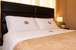a bed with white pillows and a black headboard at Hotel Zackenbarsch in Huánuco