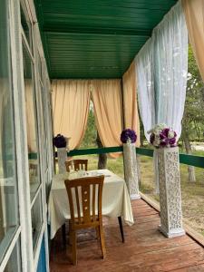 a porch with a table and chairs and flowers at Хостел 9 коттедж in Cholpon-Ata