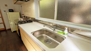 a kitchen counter with a sink in a kitchen at ゲストハウスヒスイ in Kuchi-sada