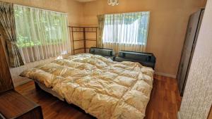 a large bed in a bedroom with two windows at ゲストハウスヒスイ in Kuchi-sada