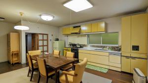 a kitchen with a table and chairs in a room at ゲストハウスヒスイ in Kuchi-sada