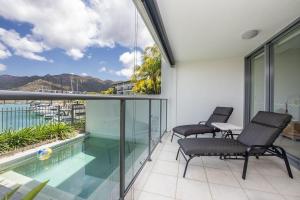a balcony with two chairs and a swimming pool at Blue on Blue Apartment 1015 in Nelly Bay
