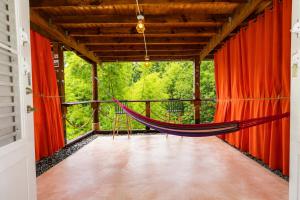 a hammock in a room with red curtains at Finca Ki' - Eco Farm Stay Bed & Breakfast - El Yunque Region in Naguabo