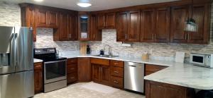 a kitchen with wooden cabinets and stainless steel appliances at Pondside Abode in Dundee