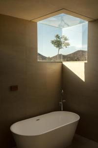 a bath tub in a bathroom with a window at Nangi Hotel Boutique in Valle de Guadalupe