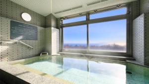 a bath room with a tub with a large window at ゆるり熱海withDOGS in Atami