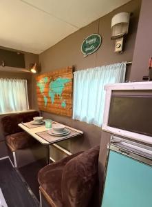 a living room with a table and a tv at Cozy Vintage Camper, the Tealy Wheely in Golden