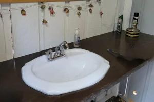 a white sink in a bathroom with a counter at Cozy Vintage Camper, the Tealy Wheely in Golden