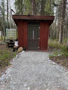 a red shed with a door in the woods at Cozy Vintage Camper, the Tealy Wheely in Golden