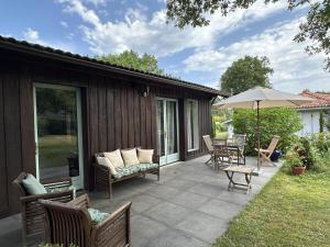 a patio with a table and chairs and an umbrella at Bois sauvage in Parentis-en-Born