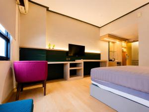ein Schlafzimmer mit Bett und Schreibtisch mit Fernseher in der Unterkunft Summerday Hotel in Ulin