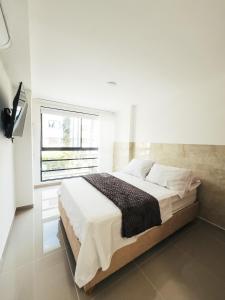 a white bedroom with a large bed with a window at Colseguros in Cali