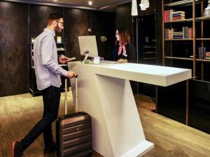a man with a suitcase walking past a reception desk at Mercure Madrid Centro in Madrid