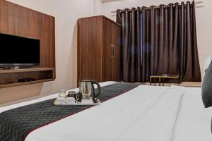 a hotel room with a bed and a tv at Super Townhouse Hotel O Benchmark in Indore +17 photos