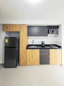 a kitchen with a black refrigerator and wooden cabinets at Colseguros in Cali