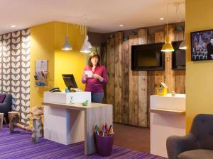 a woman standing in a room with a counter at ibis Styles Chaumont Centre Gare in Chaumont
