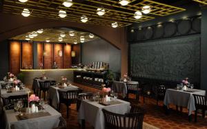a dining room with tables and chairs with flowers on them at The Palace Indochine Hotel in Siem Reap