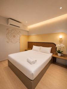 a bedroom with a large white bed with a white towel on it at ISA Hotel Amber Road in Singapore