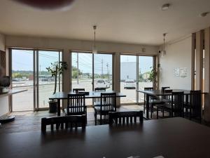 a dining room with tables and chairs and windows at Hotel The Namie Terrace in Namie