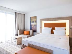 a hotel room with a large bed and a chair at Novotel Nürnberg Centre Ville in Nuremberg
