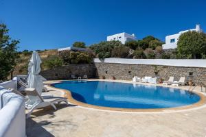 a swimming pool with chairs and a building at Belogna Ikons in Vívlos